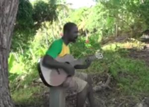 Le musicien répète avec une guitare acoustique sous un manguier